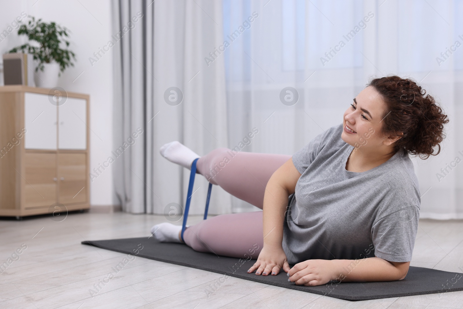 Photo of Woman training with resistance band at home