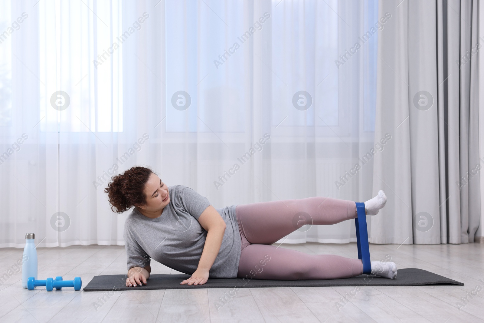 Photo of Woman training with resistance band at home