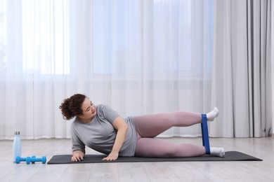 Photo of Woman training with resistance band at home