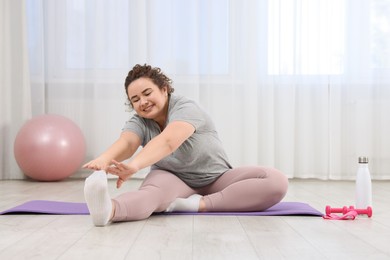 Photo of Woman stretching during training on fitness mat at home