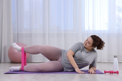 Photo of Woman training with resistance band at home