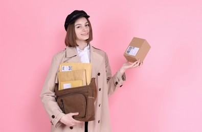 Photo of Happy postwoman with bag and parcel on pink background. Space for text