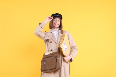 Photo of Happy postwoman with bag and envelopes on yellow background