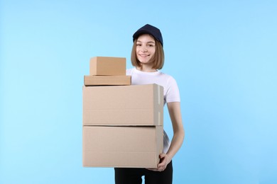 Photo of Happy postwoman with parcels on light blue background