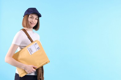 Photo of Happy postwoman with bag and envelopes on light blue background. Space for text