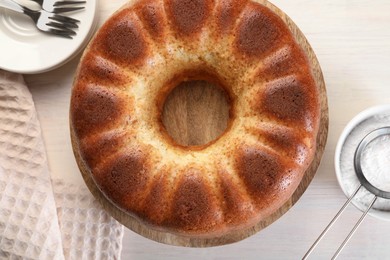 Photo of Freshly baked sponge cake served on white wooden table, top view