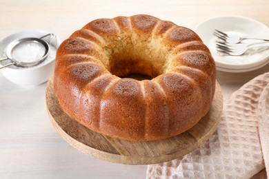 Photo of Freshly baked sponge cake served on white wooden table, closeup