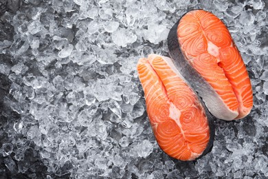 Photo of Fresh raw salmon steaks on ice pieces, flat lay. Space for text