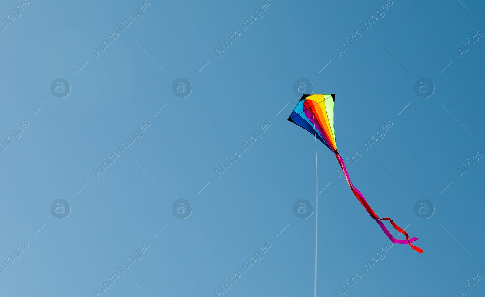 One colorful kite flying in blue sky. Space for text Photo of One colorful kite flying in blue sky. Space for text