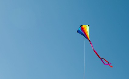 Photo of One colorful kite flying in blue sky. Space for text