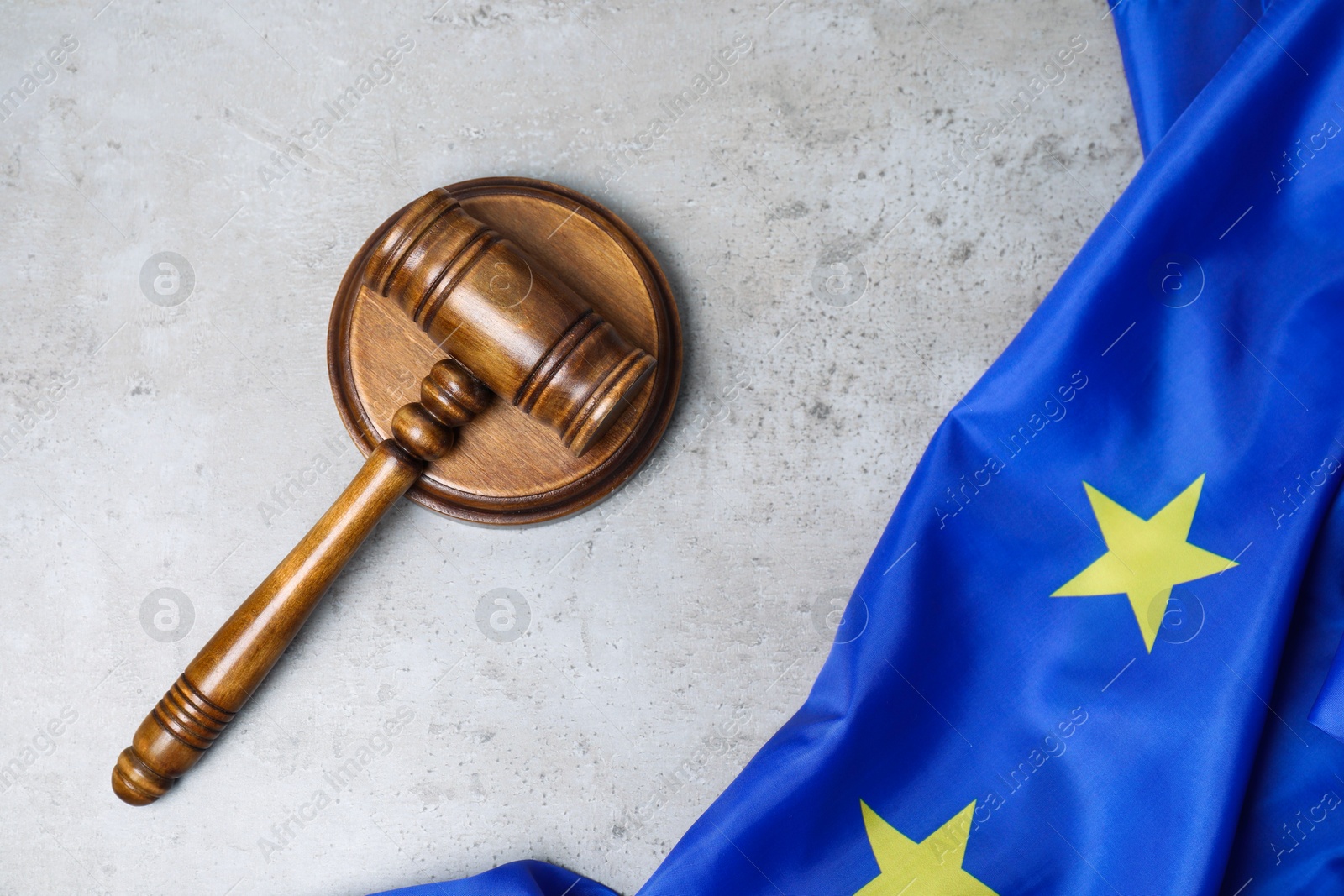 Photo of Judge's gavel and flag of European Union on grey table, top view