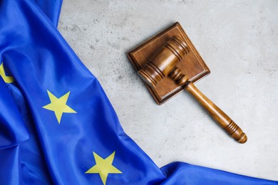 Photo of Judge's gavel and flag of European Union on grey table, top view