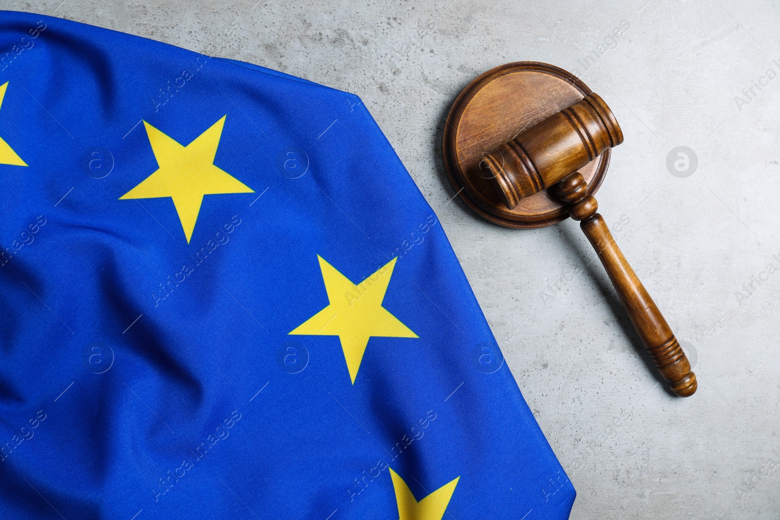 Photo of Judge's gavel and flag of European Union on grey table, top view