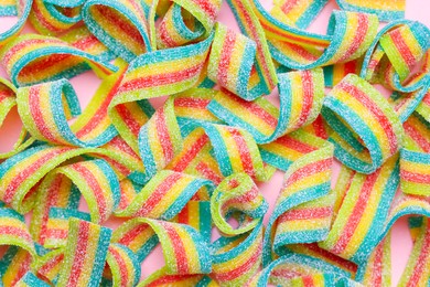 Photo of Tasty rainbow sour belts on pink background, top view