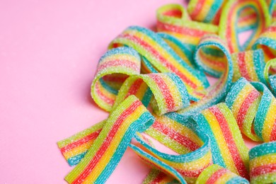 Photo of Tasty rainbow sour belts on pink background, closeup. Space for text