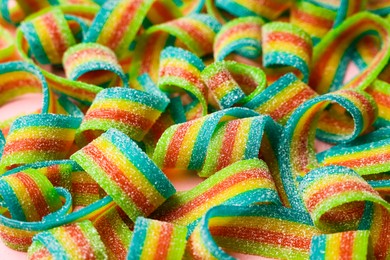 Photo of Tasty rainbow sour belts on pink background, closeup