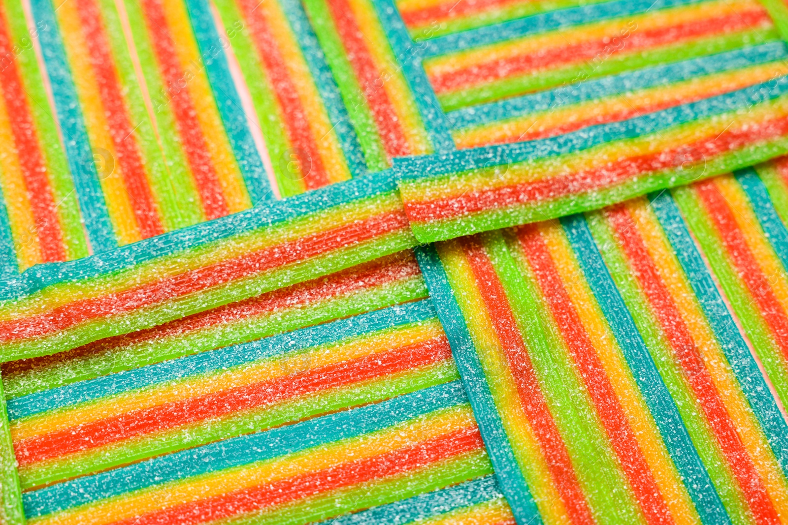 Photo of Tasty rainbow sour belts as background, closeup