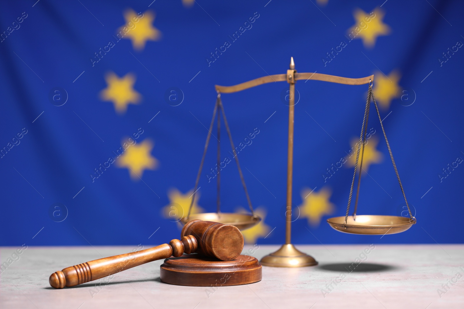 Photo of Scales of justice and judge's gavel on table against European Union flag