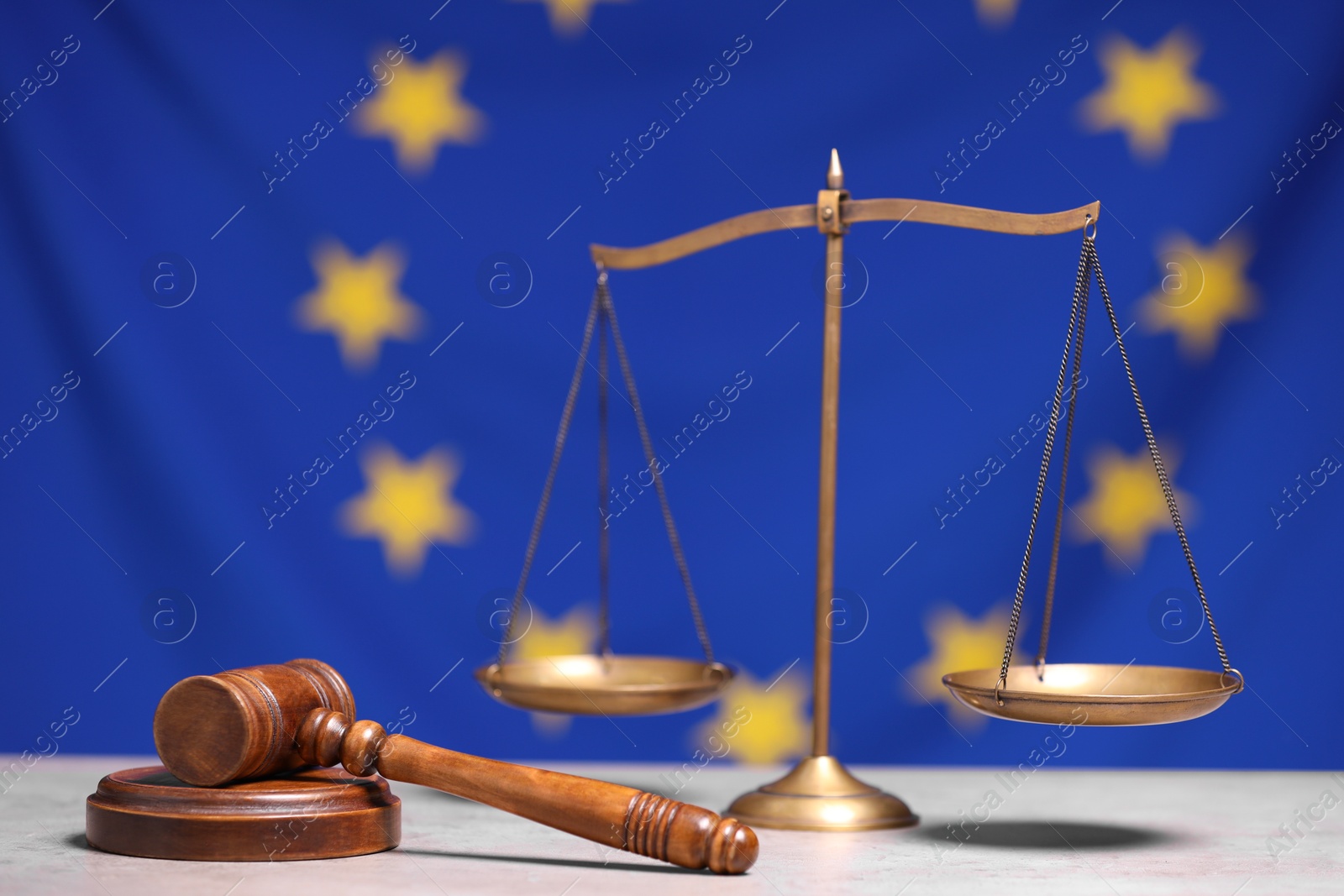 Photo of Scales of justice and judge's gavel on table against European Union flag