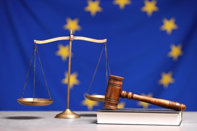 Photo of Scales of justice, judge's gavel and book on table against European Union flag