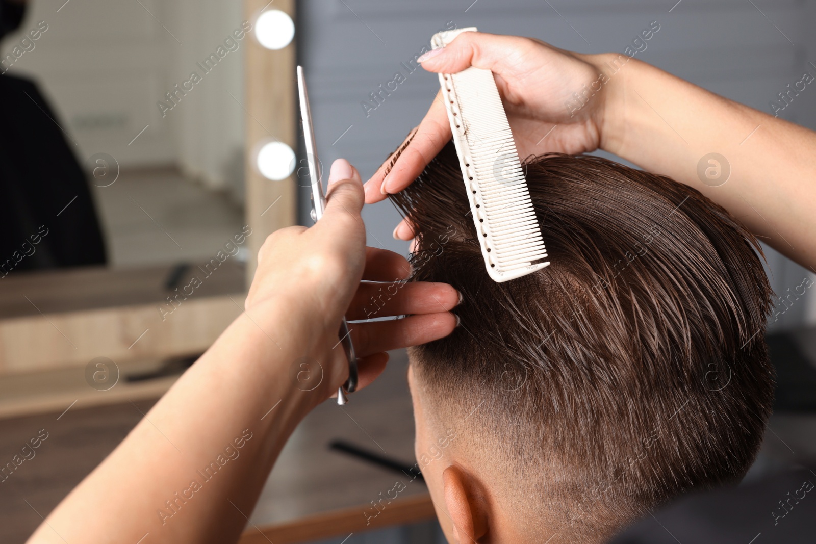 Photo of Professional hairdresser cutting client's hair with scissors in barbershop, closeup