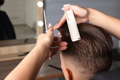 Photo of Professional hairdresser cutting client's hair with scissors in barbershop, closeup