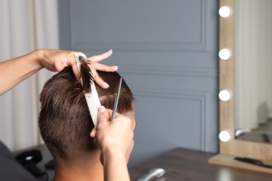 Photo of Hair cutting. Hairdresser combing man's hair in barbershop, closeup. Space for text