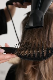 Photo of Hairdresser blow drying client's hair in salon, closeup