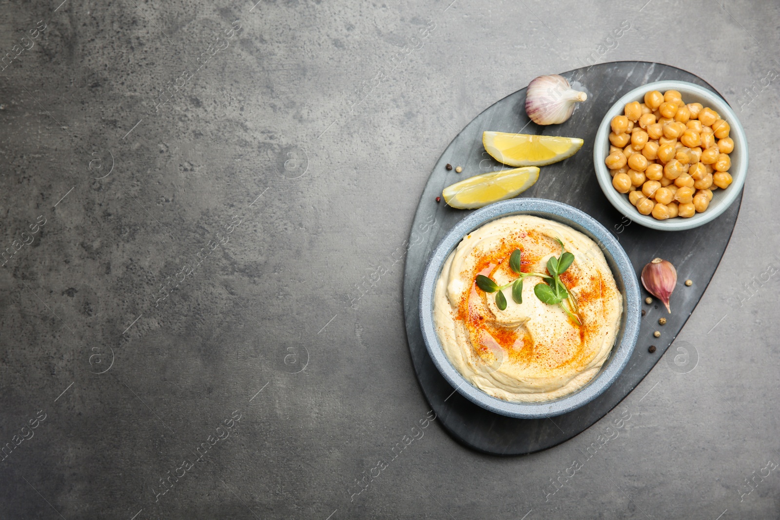 Photo of Delicious hummus with paprika and chickpeas served on dark grey table, flat lay. Space for text