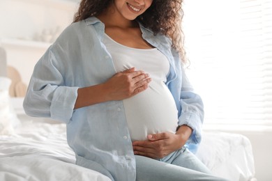 Photo of Pregnant woman on bed at home, closeup