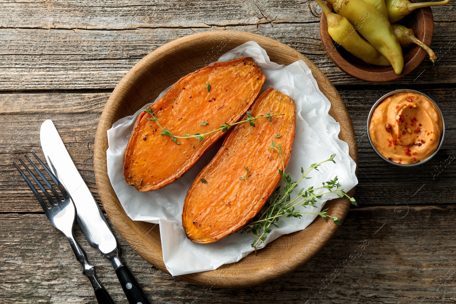 Photo of Tasty cooked sweet potato served with thyme and sauce on wooden table, top view