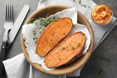 Photo of Tasty cooked sweet potato served with thyme and sauce on grey table, top view