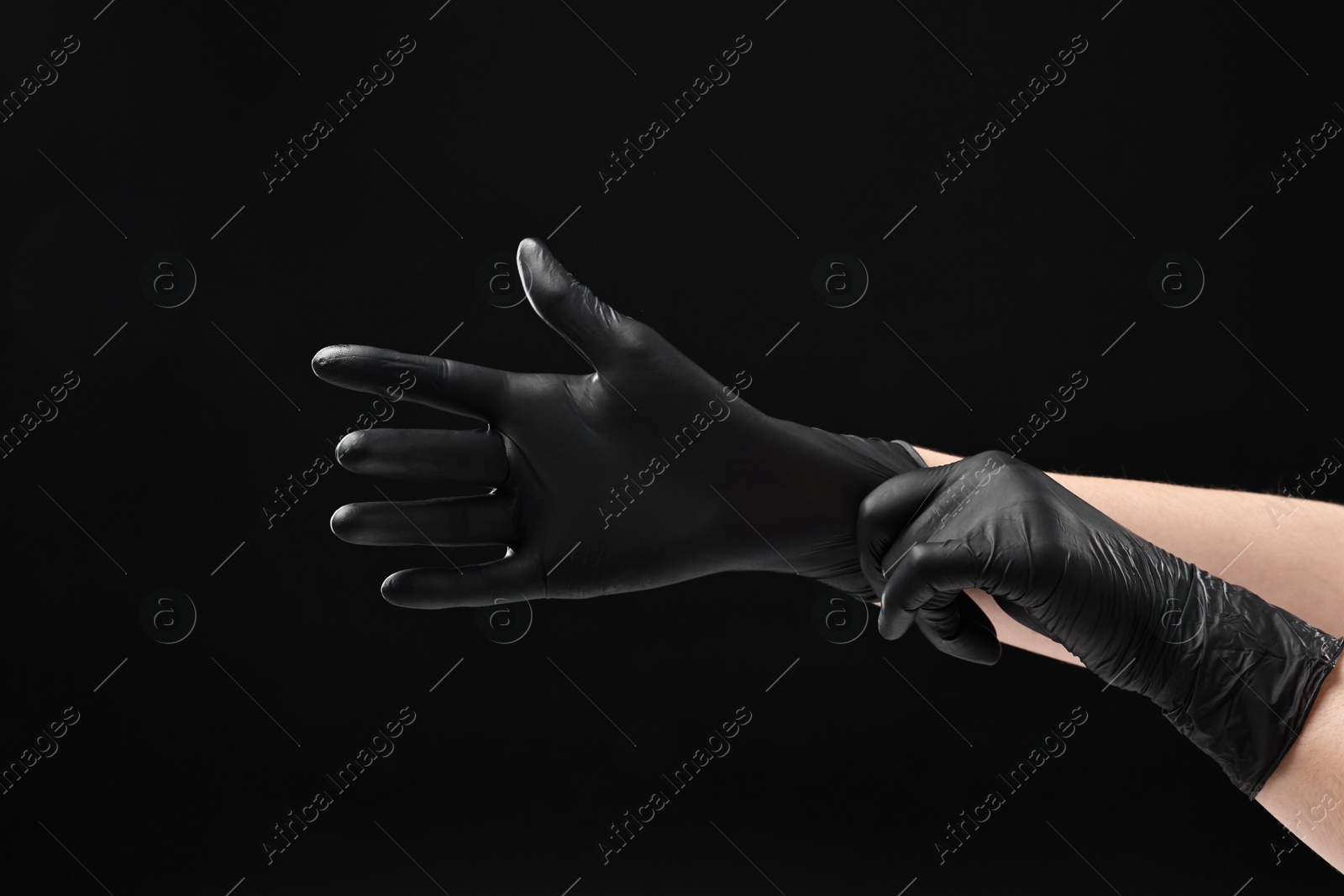 Photo of Man wearing latex gloves on black background, closeup