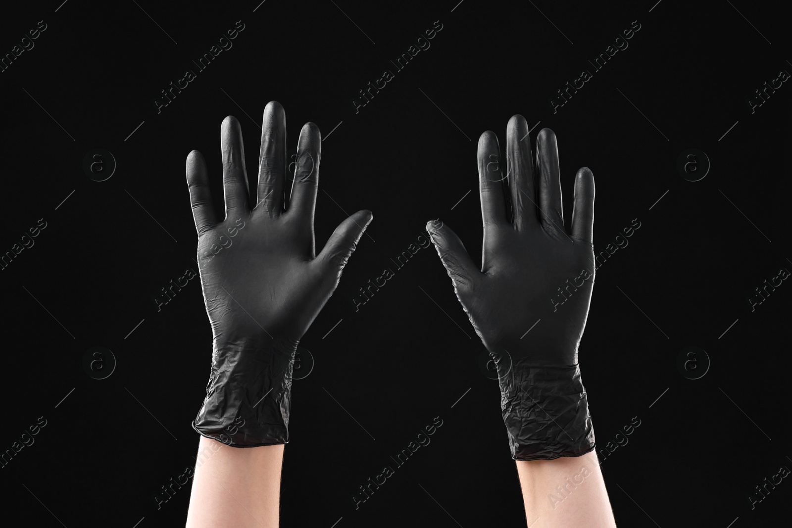 Photo of Man wearing latex gloves on black background, closeup