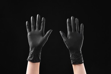 Photo of Man wearing latex gloves on black background, closeup