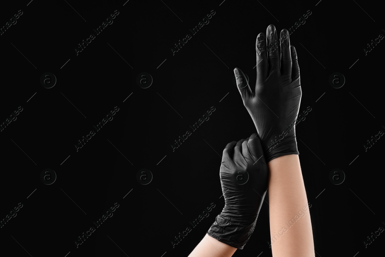 Photo of Man wearing latex gloves on black background, closeup. Space for text