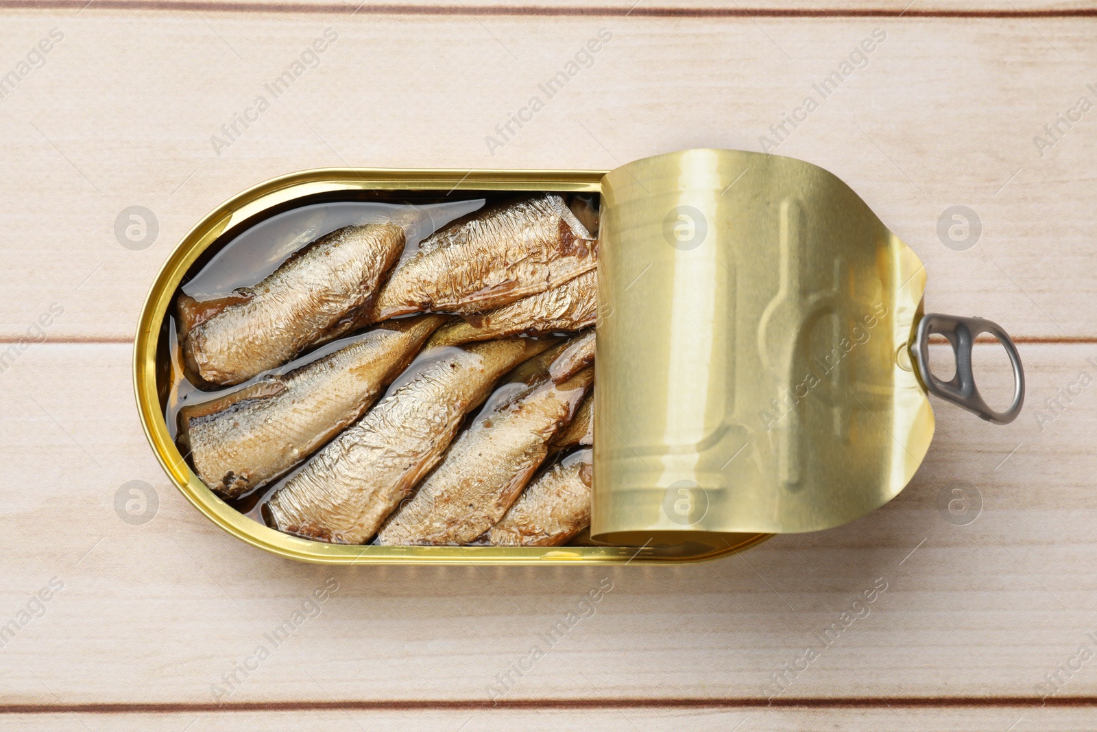 Photo of Tasty sprats in tin can on wooden table, top view