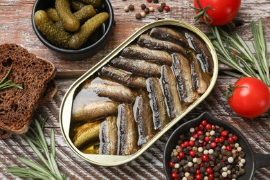 Photo of Tasty sprats in tin can served on wooden table, flat lay