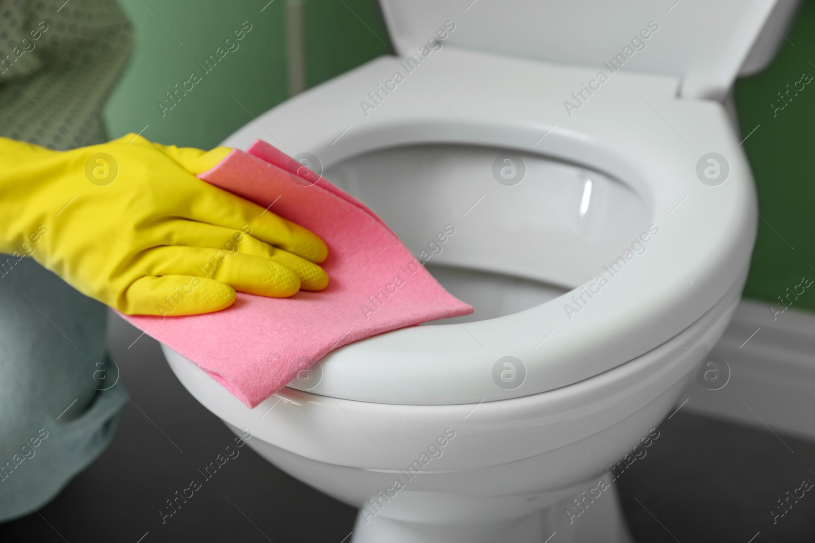 Photo of Woman cleaning toilet seat in restroom, closeup