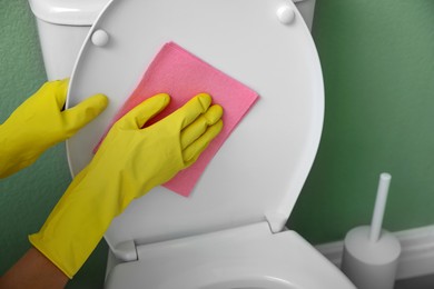 Photo of Woman cleaning toilet lid in restroom, closeup