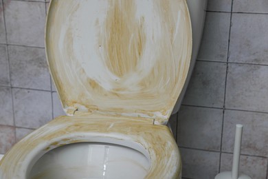 Photo of Toilet with dirty seat in public restroom, closeup