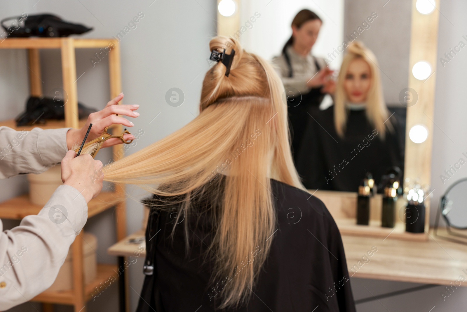 Photo of Hairdresser cutting client's hair with scissors in salon, closeup