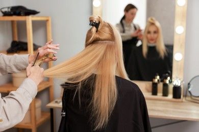 Photo of Hairdresser cutting client's hair with scissors in salon, closeup