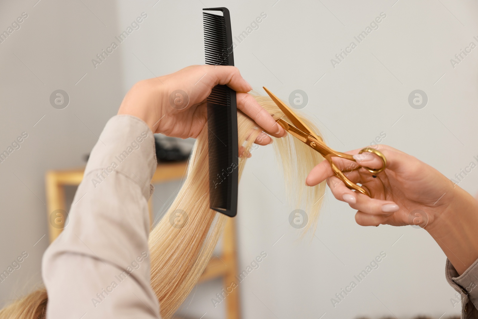 Photo of Hairdresser cutting client's hair with scissors in salon, closeup