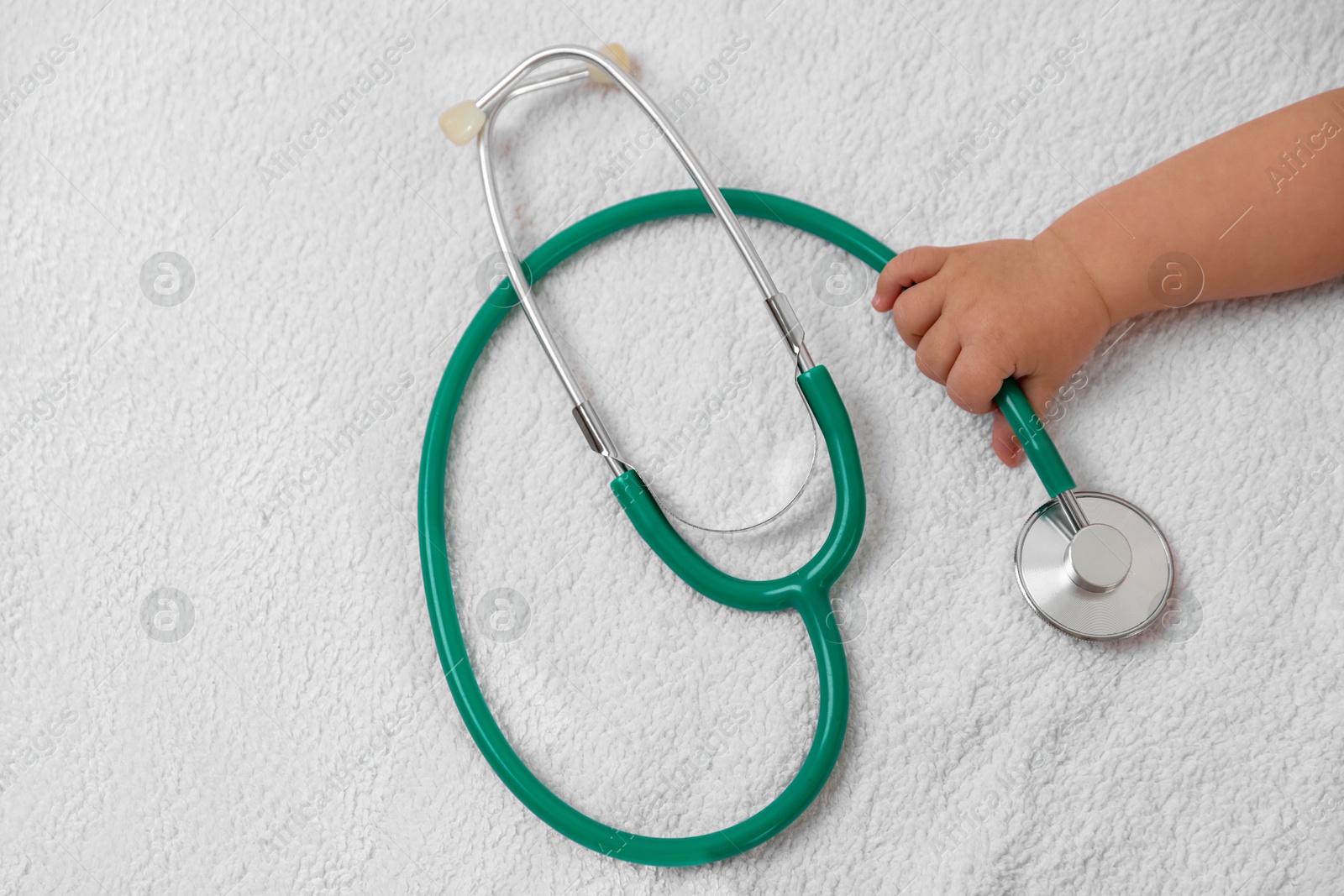 Photo of Little child with stethoscope on towel, top view. Checking baby's health