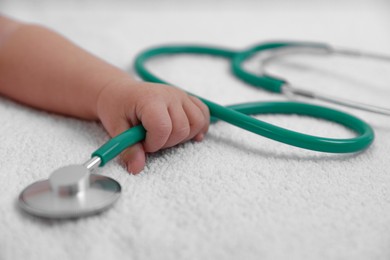 Photo of Little child with stethoscope on towel, closeup. Checking baby's health