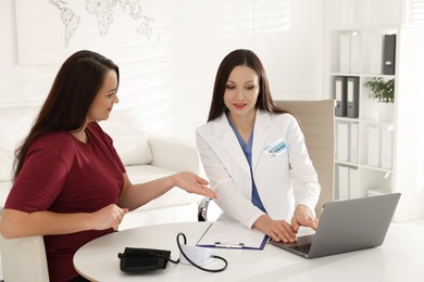 Photo of Overweight woman having consultation with nutritionist at desk in clinic