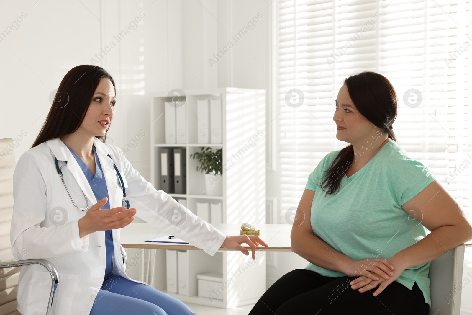 Photo of Nutritionist giving recommendations to overweight woman in hospital