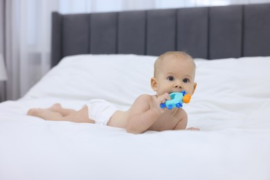 Photo of Cute little baby with rattle on bed indoors