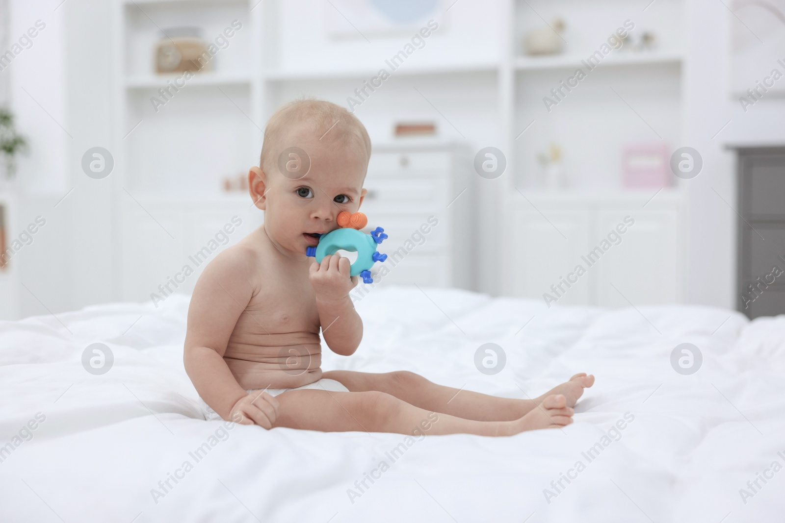 Photo of Cute little baby with rattle on bed indoors, space for text